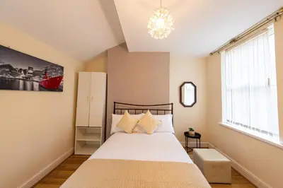 a bedroom with a bed and a chandelier at Holly Room in Liverpool