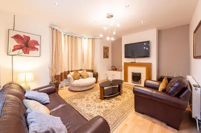 a living room with a leather couch and a fireplace at Holly Room in Liverpool