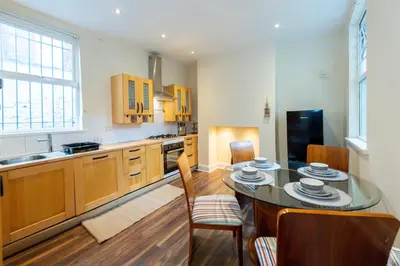 a kitchen with a table and chairs and a kitchen with a sink at Holly Room in Liverpool