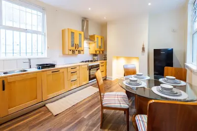 a kitchen with wooden cabinets and a table and chairs at Holly Room in Liverpool