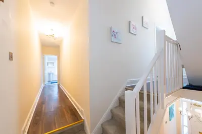 a staircase in a home with white walls and wooden floors at Holly Room in Liverpool