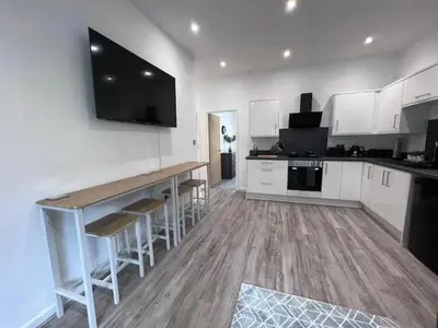 a kitchen with white cabinets and a bar with stools at Monthly Stays Liverpool in Liverpool