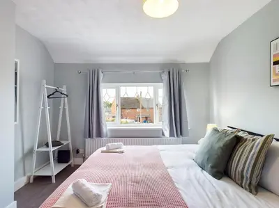 a bedroom with a white bed with a window at Stunning Family Home with Comfortable Surroundings by Our Home Short Stays ideally situated within Greater Manchester in Hindley