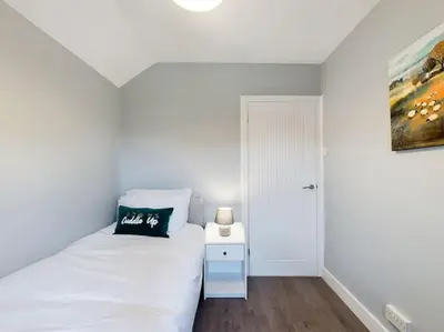 a bedroom with a white bed with a black pillow on it at Stunning Family Home with Comfortable Surroundings by Our Home Short Stays ideally situated within Greater Manchester in Hindley