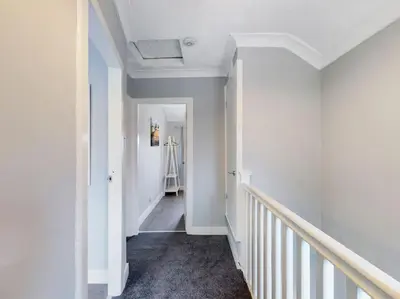 a hallway with white walls and a white stairway at Stunning Family Home with Comfortable Surroundings by Our Home Short Stays ideally situated within Greater Manchester in Hindley
