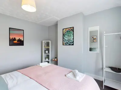 a bedroom with a bed with a pink blanket at Stunning Family Home with Comfortable Surroundings by Our Home Short Stays ideally situated within Greater Manchester in Hindley