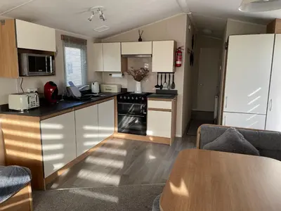 a kitchen with white cabinets and a table in a room at Ocean Edge Morecambe Sea view in Heysham