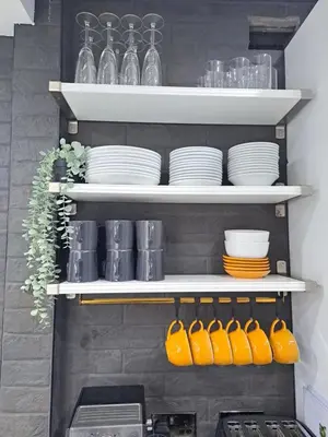 a kitchen with white shelves with plates and bowls at Family Holiday with Hot tub , Family groups only in Blackpool
