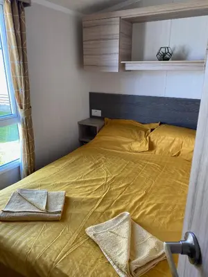 a bedroom with a bed with yellow sheets and a window at Swift Retreat Caravan - Morecambe in Morecambe
