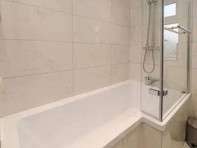a white bathroom with a tub and a shower at 37 Nutter Road in Cleveleys
