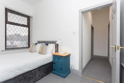 a bedroom with a bed with a blue nightstand and a window at The Station House in Preston