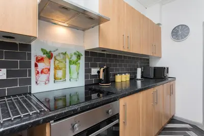 a kitchen with wooden cabinets and a black counter top at The Station House in Preston