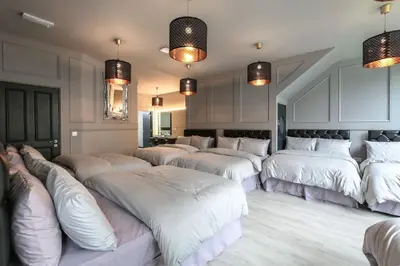 a room with a bunch of white beds in it at Manhattan Suite - sleeps 24! Heart of Liverpool in Liverpool