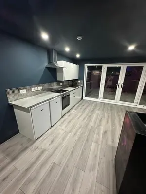 a kitchen with white cabinets and a wooden floor at Penthouse Apartment, Sleeps 21 with terrace in Liverpool