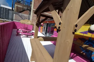 a wooden deck with pink and purple tables and chairs at Penthouse Apartment, Sleeps 21 with terrace in Liverpool