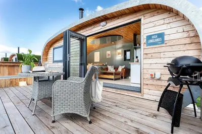 a house with a deck with chairs and a grill at High Longlands in Cartmel