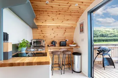a kitchen with wood paneling and a counter with stools at High Longlands in Cartmel