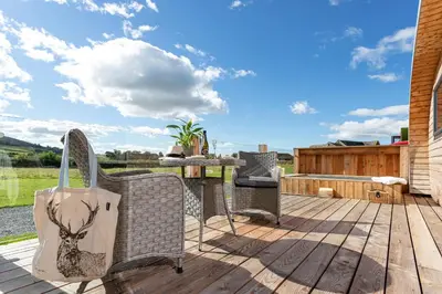 a deck with chairs and a table with a shopping bag at High Longlands in Cartmel