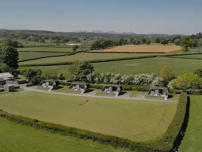 an aerial view of a large green field with domes at High Longlands in Cartmel