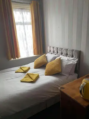 a bed with two yellow pillows and a window at JEANNE in Blackpool