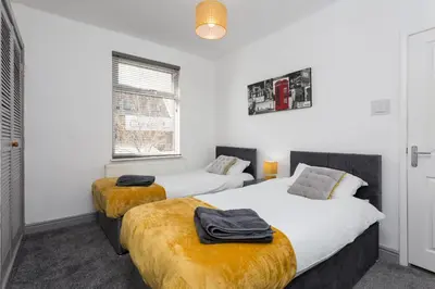 two beds in a room with white walls at No 1 School House in Leyland