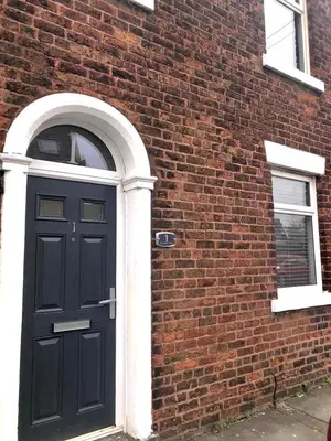 a black door on the side of a brick building at No 1 School House in Leyland