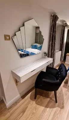 a mirror on a wall with a black chair and a chair at Sea-Quinn Views in Wallasey