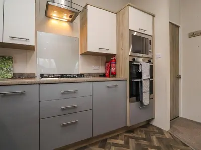 a kitchen with white cabinets and a stove top oven at Fountain View in Carnforth