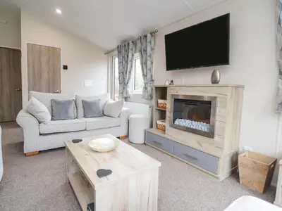 a living room with a couch and a tv on the wall at Fountain View in Carnforth