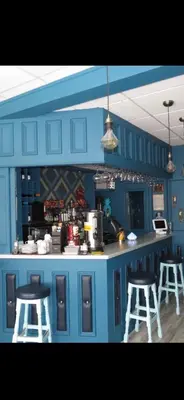 a blue kitchen with two stools and a counter at By the Seaside in Blackpool