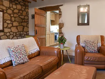 a living room with leather furniture and a stone wall at Shire Nooks in Hurst Green