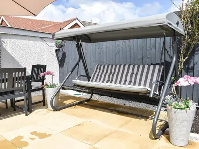 a bench under an umbrella on a patio at Newcastle Lodges in Thornton