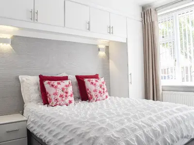 a bedroom with a large white bed with red pillows at Newcastle Lodges in Thornton