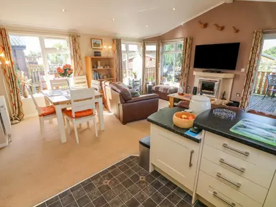 a kitchen and living room with a table and a television at Mallard Lodge in Carnforth