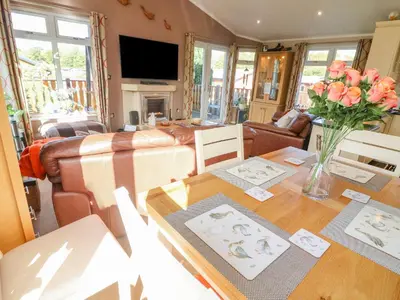 a living room with a table with flowers on it at Mallard Lodge in Carnforth