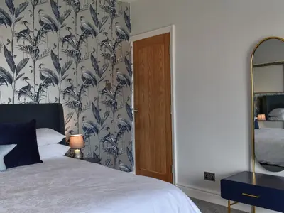 a bedroom with a bed with a blue and white wallpaper at Ted's Place in Arnside