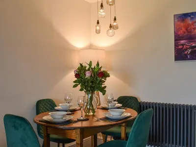 a dining room table with a vase of flowers at Ted's Place in Arnside