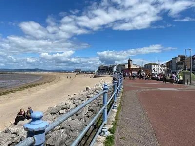 a beach with a blue fence and people on the beach at Quiet Ground Floor apartment with parking in Morecambe