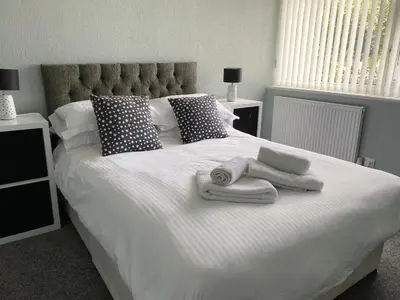 a white bed with towels and pillows on it at Quiet Ground Floor apartment with parking in Morecambe