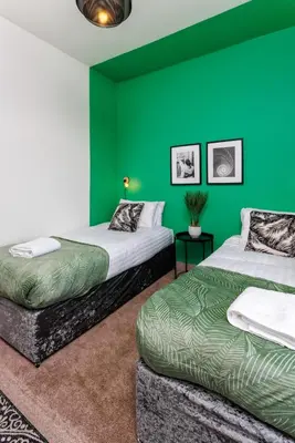 two beds in a room with green walls at Hornsey House - Air Host & Stay - 5 Bedrooms Sleeps 10 in Liverpool