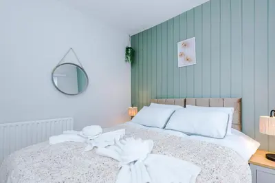 a bedroom with a bed with white sheets and a mirror at Trendy house, close to stadiums, free wifi and car park in Liverpool
