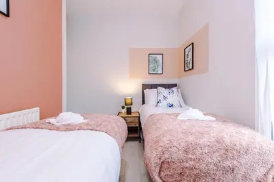 a bedroom with two beds and a table with a lamp at Trendy house, close to stadiums, free wifi and car park in Liverpool
