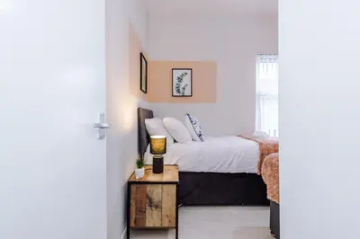 a small bedroom with a bed and a table at Trendy house, close to stadiums, free wifi and car park in Liverpool