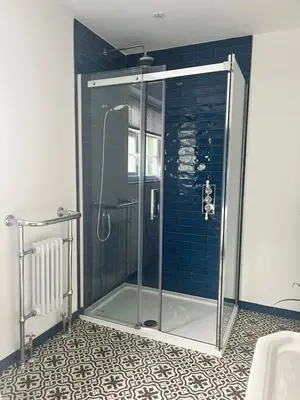 a shower in a bathroom with blue tiles at The Nutshell in Southport