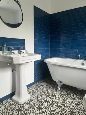 a bathroom with a tub and a sink and blue tiles at The Nutshell in Southport