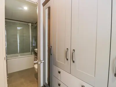 a bathroom with white cabinets and a shower at Hudson's Hideaway in Carnforth