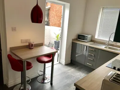 a small kitchen with a table and two red stools at 77 Park Road Apartments in Blackpool