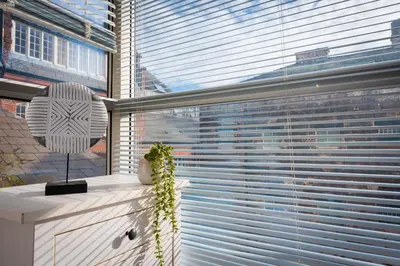 a window with blinds on it with a table with a plant at Free Parking Modern Balcony 2 Bed City Centre in Liverpool