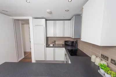 a kitchen with white cabinets and a sink at Free Parking Modern Balcony 2 Bed City Centre in Liverpool