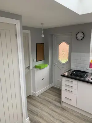 a kitchen with white cabinets and a clock on the wall at Town Centre Getaway in Southport